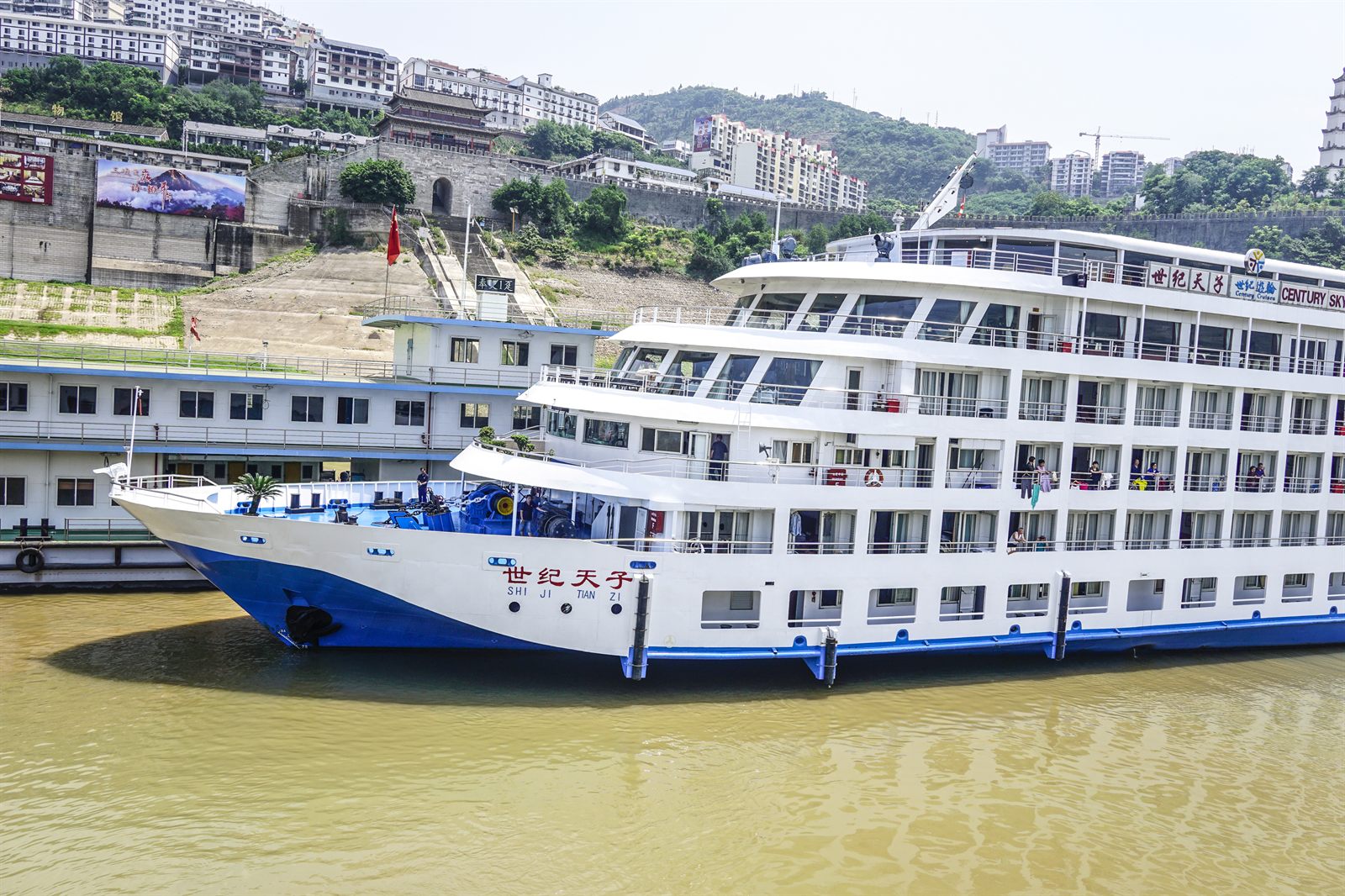 Multi-deck river cruise ship moored on the Yangtze below a hillside city, one of the classic river cruises in Asia